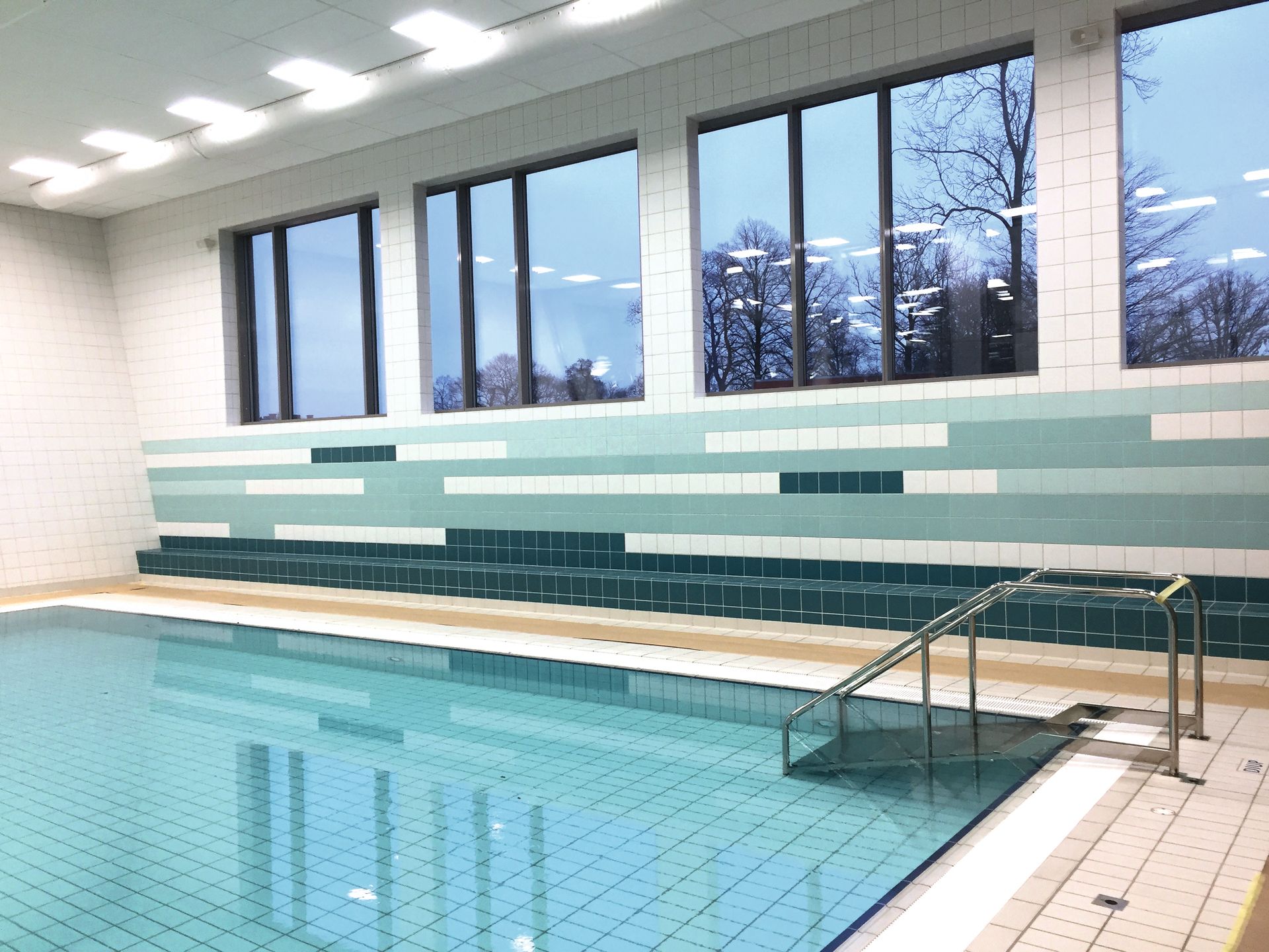 full body solid colour tiles used in a public swimming pool , metal handle bars 