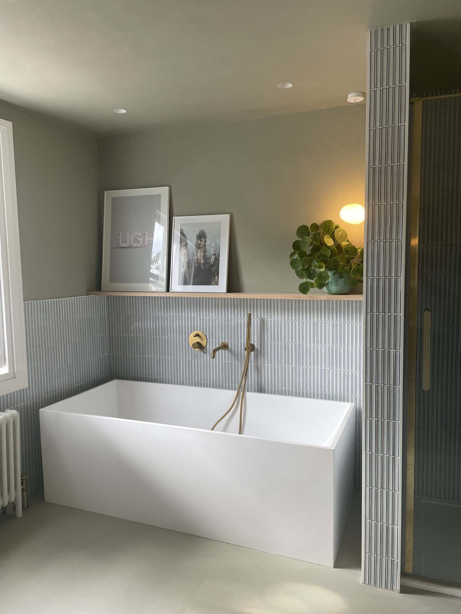 Kit Kat Gris mosaic bath surround, white bathtub and brass shower head