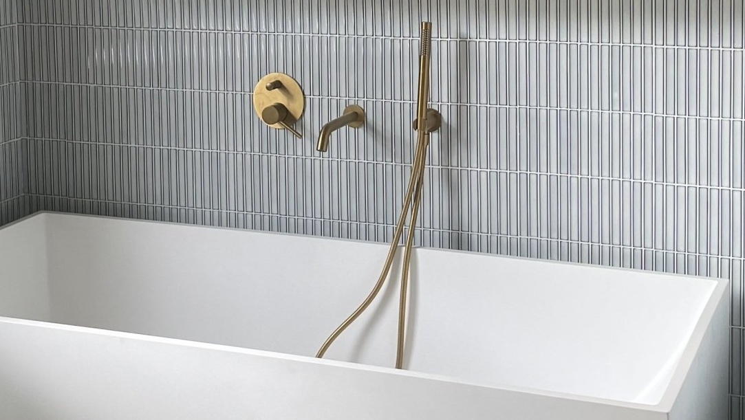 Kit kat  mosaic tiles featured on a bathroom wall behind golden bath faucets