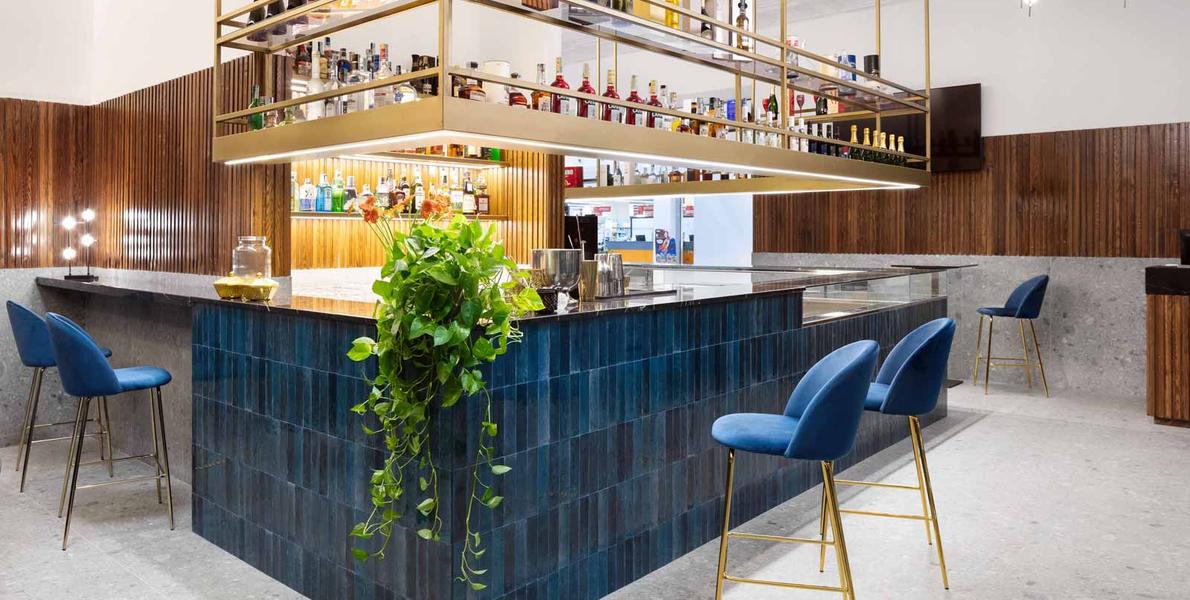 a zellige brick tile used around a blue bar front with blue seating and a hanging green plant leaves