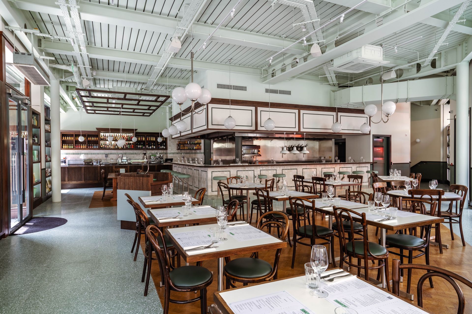 Resturant eating area with tables and chairs and a verde terrazo effect floor tile
