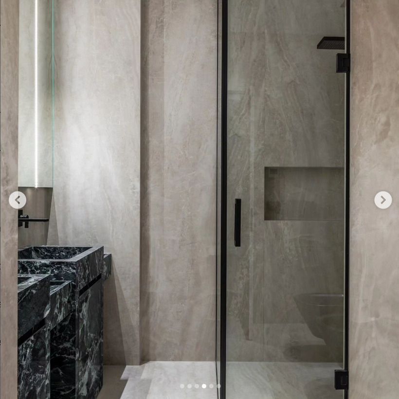 A detailed view of a bathroom featuring polished green marble walls and a countertop. The vibrant green tones are complemented by brass fixtures for a luxurious finish.