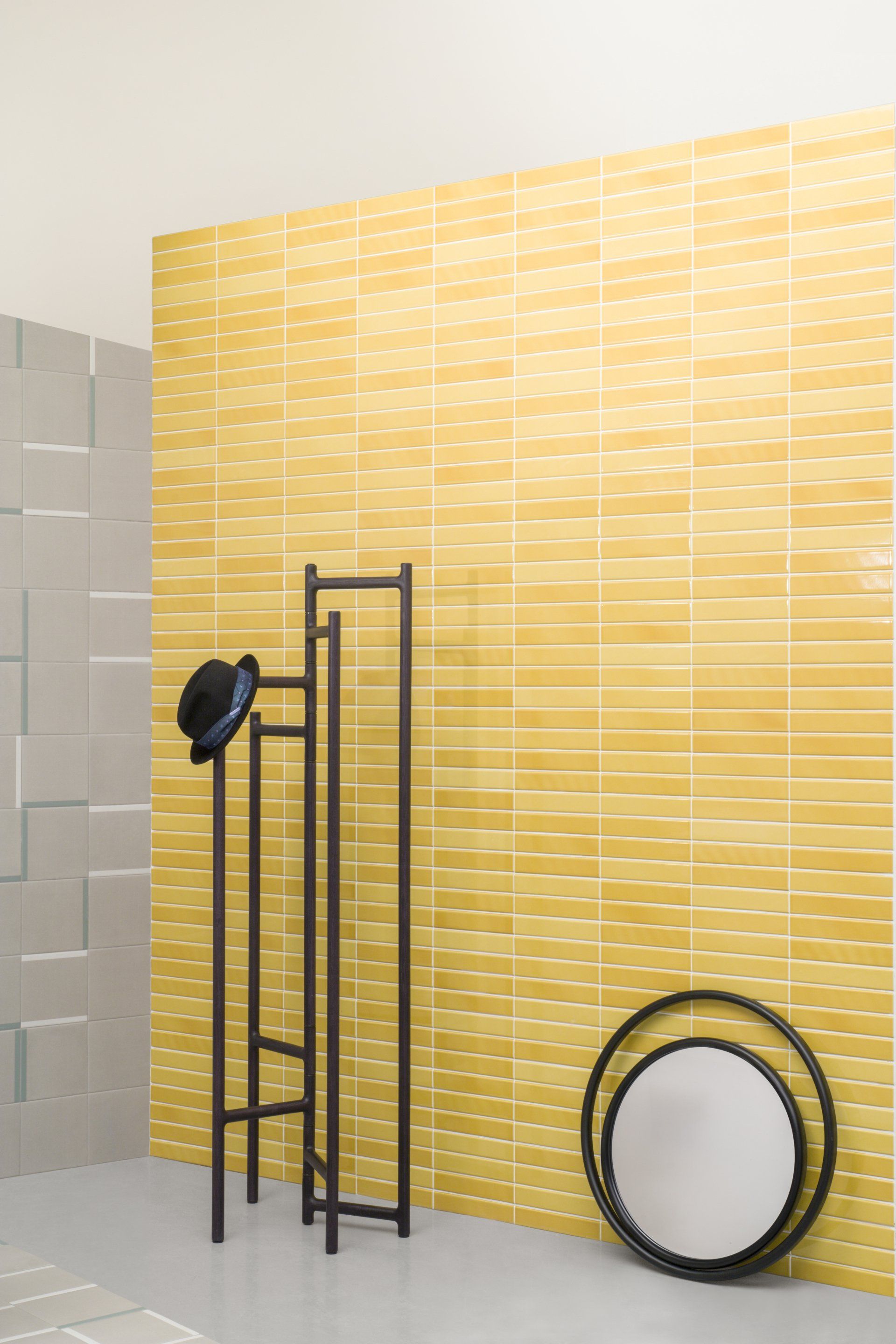 Yellow metro brick wall with white grout lines, a black hat rack and mirror