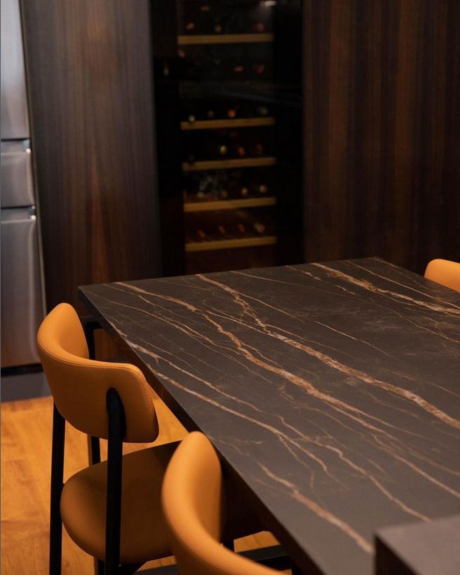 Dark marble tabletop with prominent gold veining, creating a luxurious feel for dining or kitchen spaces.