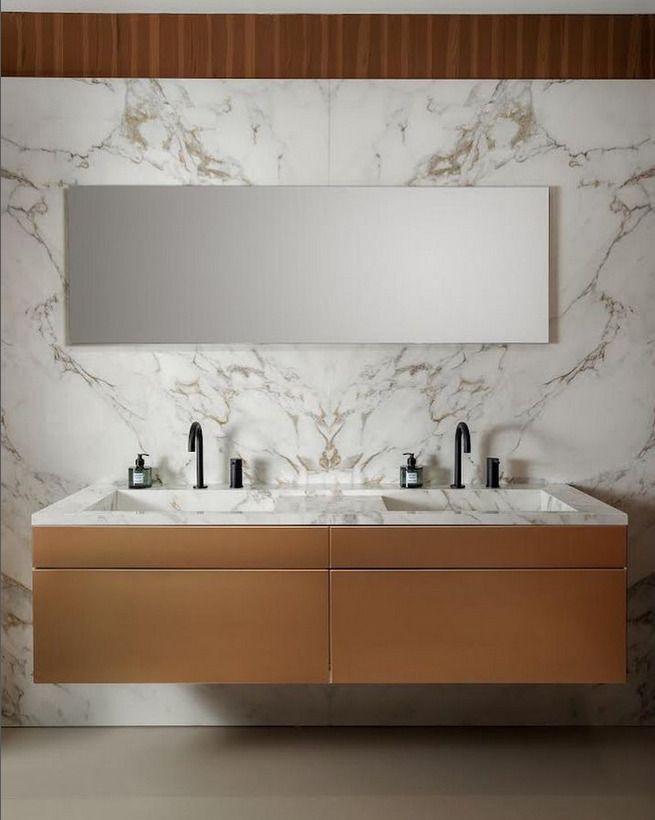 Double basin vanity with a bronze base and luxurious marble walls, adding warmth and opulence to a bathroom setting.
