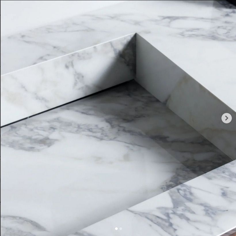 A close-up of a white marble countertop with clean edges, showcasing the detailed veining patterns in the stone.
