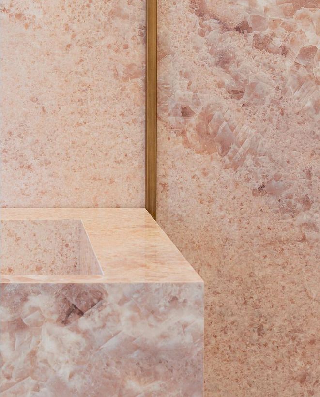 Elegant pink marble sink with a minimalist brass divider, providing a luxurious touch to the bathroom setting.