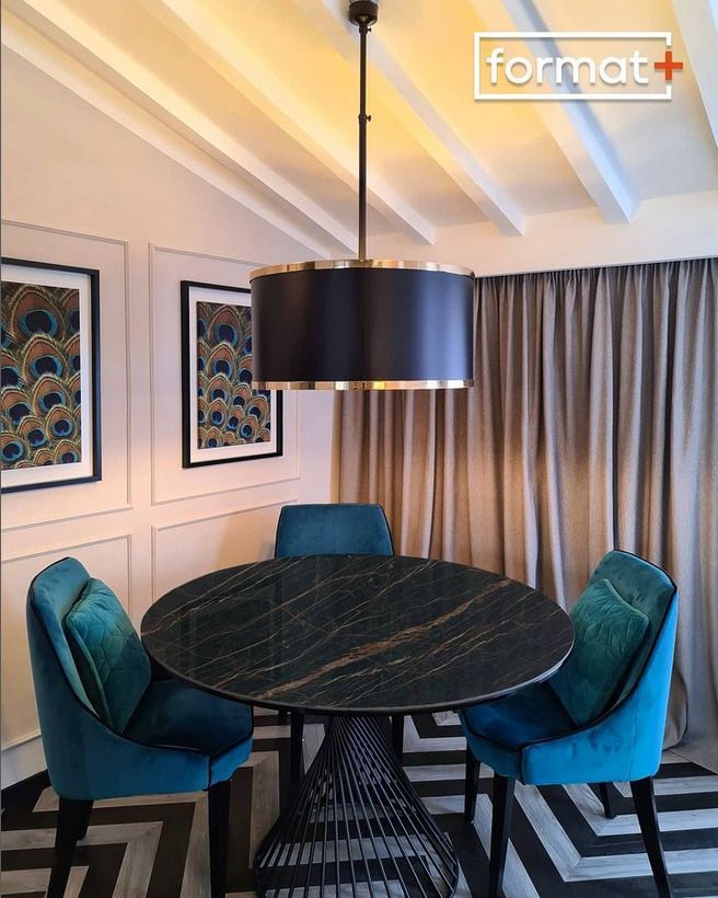 Elegant dining area featuring a black marble table and blue velvet chairs with modern lighting.