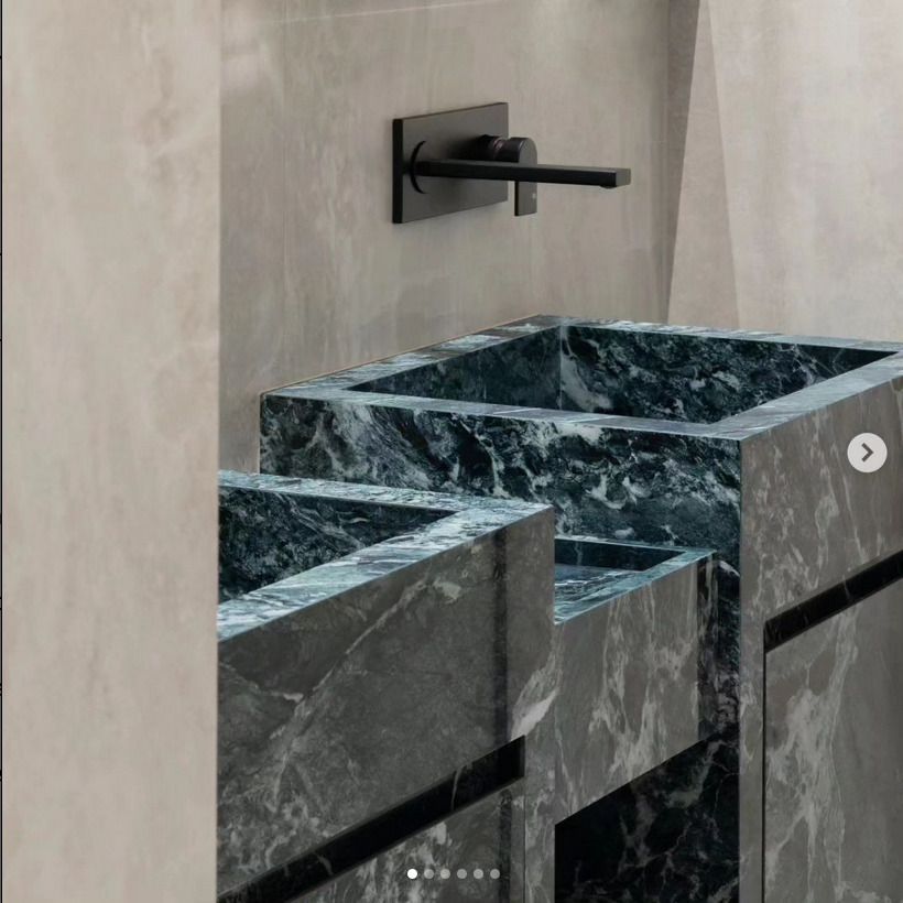 Dual green marble sinks with black fixtures in a contemporary bathroom setting.