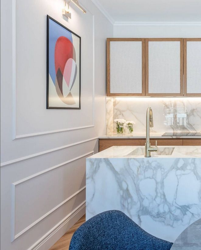 Kitchen interior with white marble countertops and backsplash, complemented by wooden cabinetry.