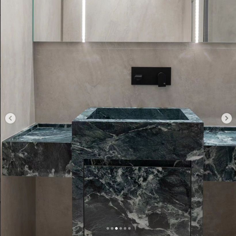 A bathroom with a striking green marble sink and vanity set, paired with minimalist black fixtures and light grey wall tiles.