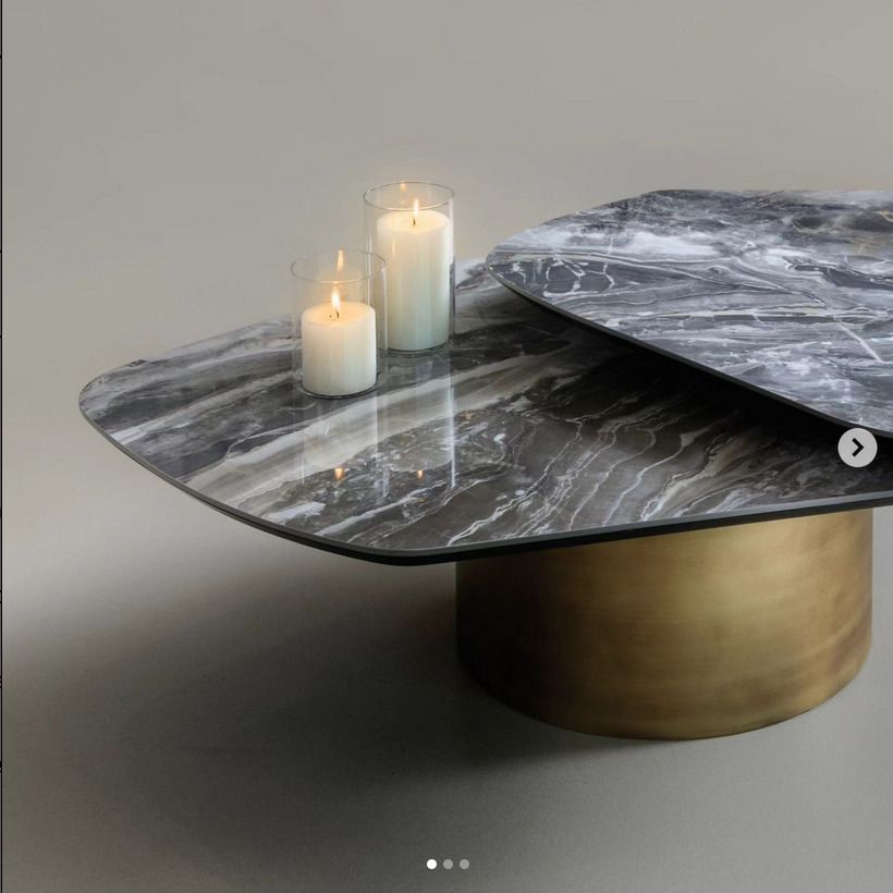 A modern coffee table with a sleek grey marble top and cylindrical gold base, displaying the elegance of natural stone surfaces.