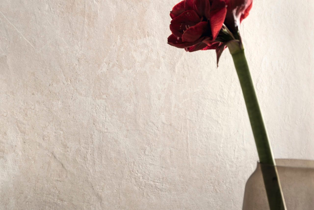 Beige textured wall tile with a red flower close-up.