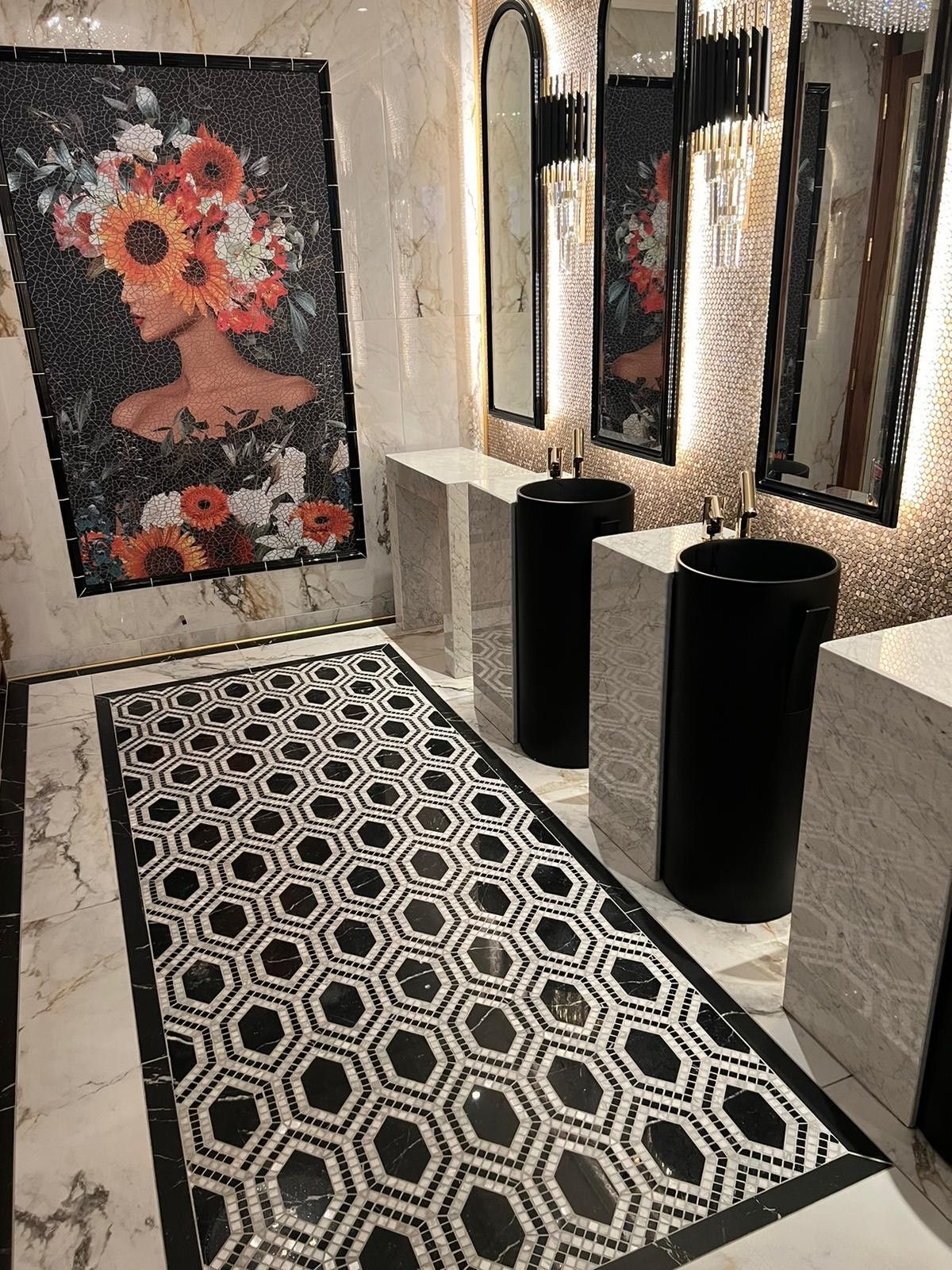 Bahthroom of mayfair casino with black sinks lights around the mirrior and patterned floor tiles