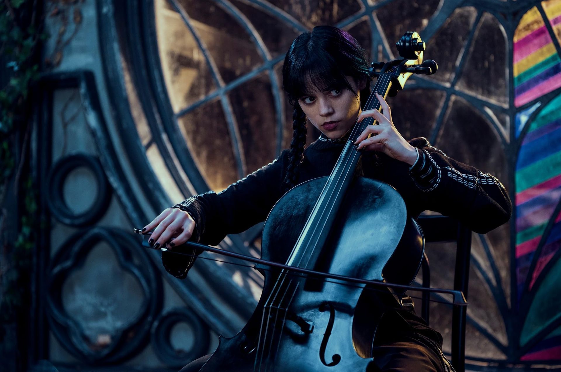 Wednesday adams outside her window at night playing the cello