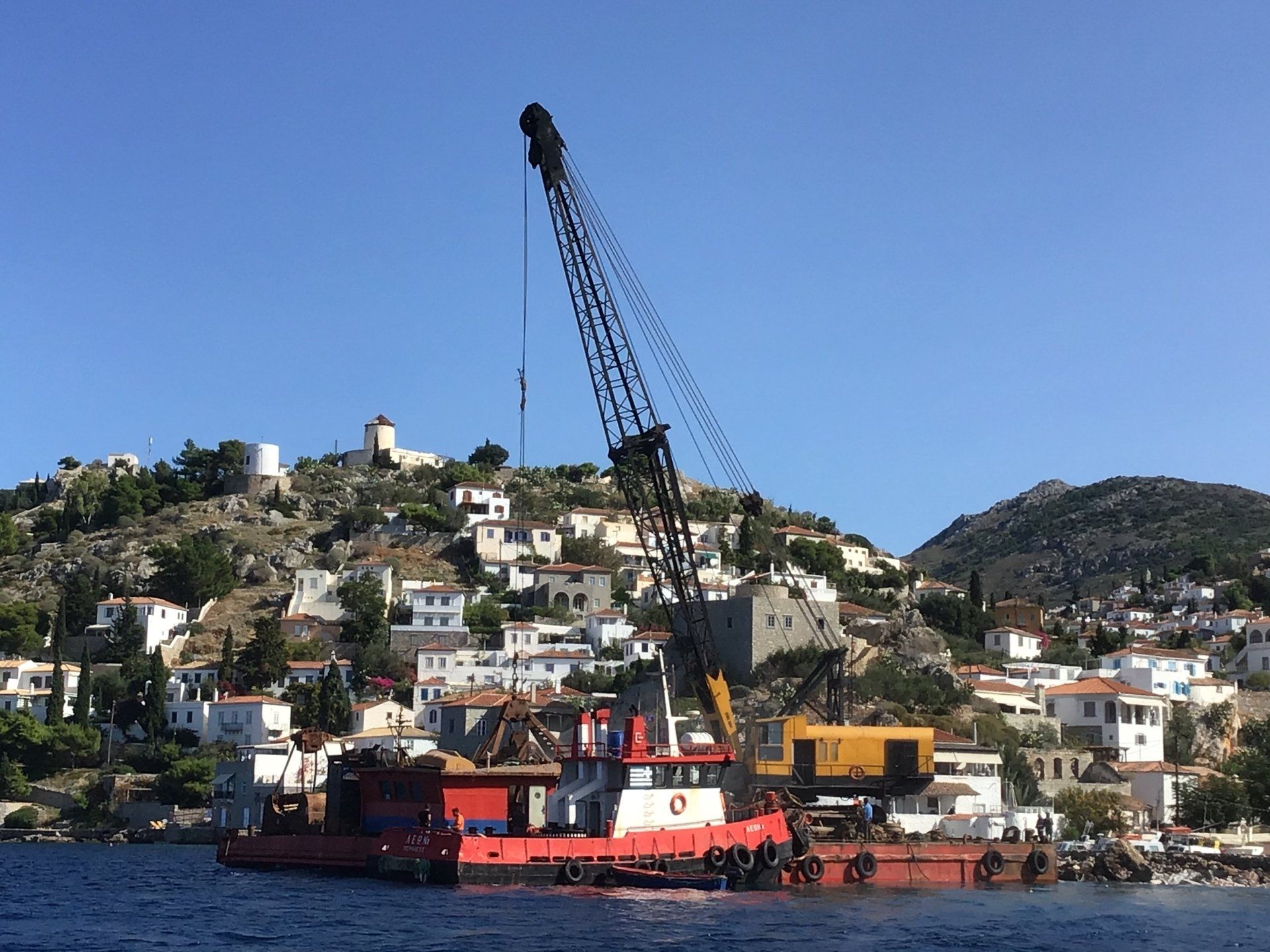 Crane barge bringing stone by sea to repair the erosion of the jetty at Kamini Harbour, Hydra.