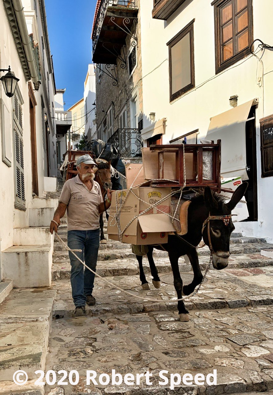 Photo by Robert Speed ©. Donkey house removal coming down Lignou Street AKA Donkey Shit Lane on Hydra Island Greece.