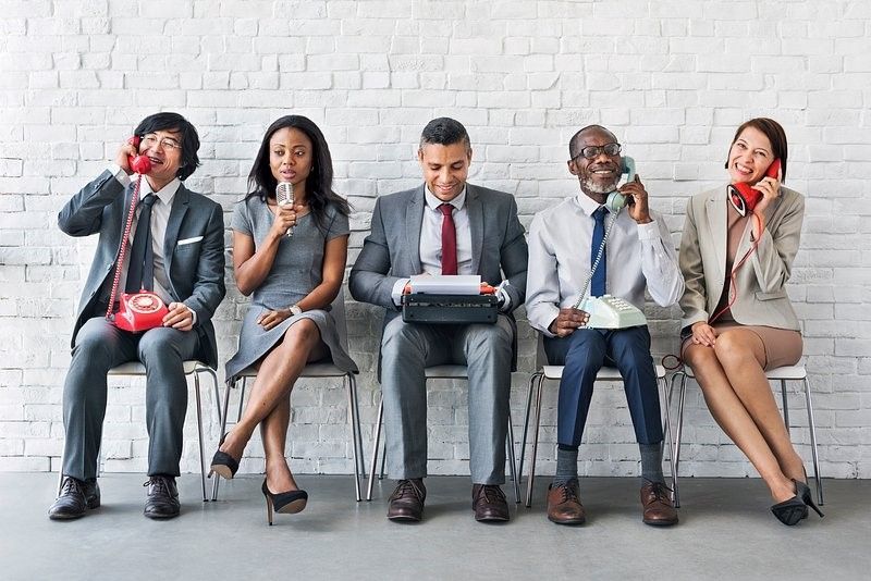 Five people professionally dressed people seated in an office setting