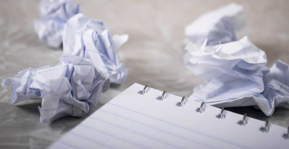 Zusammengeknülltes Papier neben einem Notizblock.