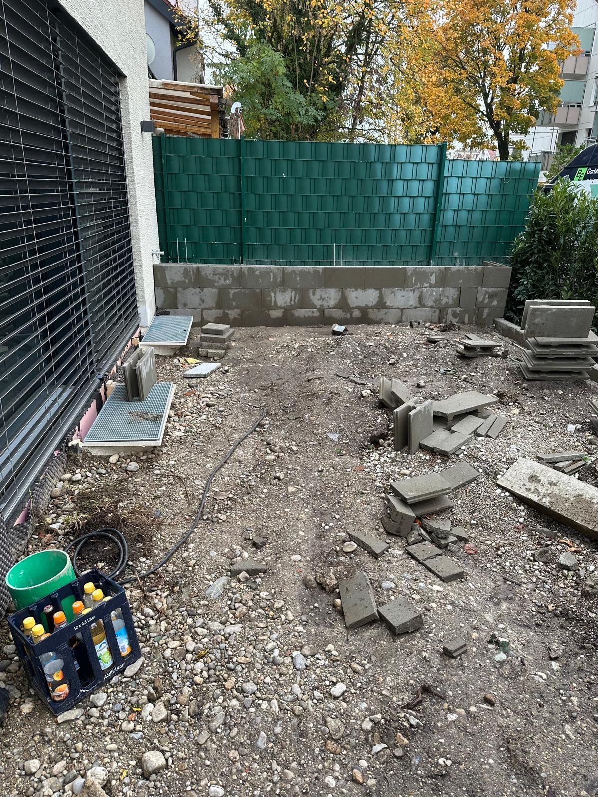 Vorher-Zustand der Terrasse in Laim: Ungepflegte Baustelle mit Schutt, alten Platten und Betonfundament vor dem neuen Terrassenbau durch BE Gartenbau München