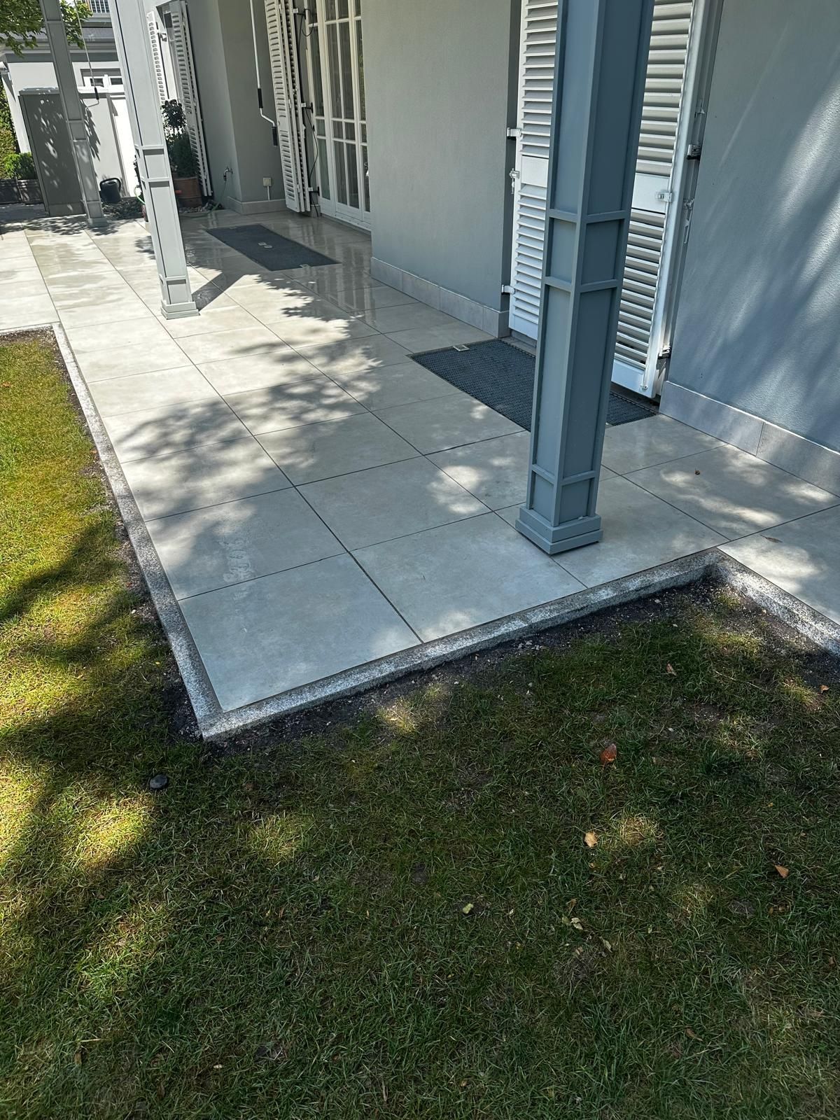 Nachher: Seitliche Ansicht der fertigen Terrasse in Obermenzing mit großformatigen Platten und Granit-Randsteinen durch BE Gartenbau München