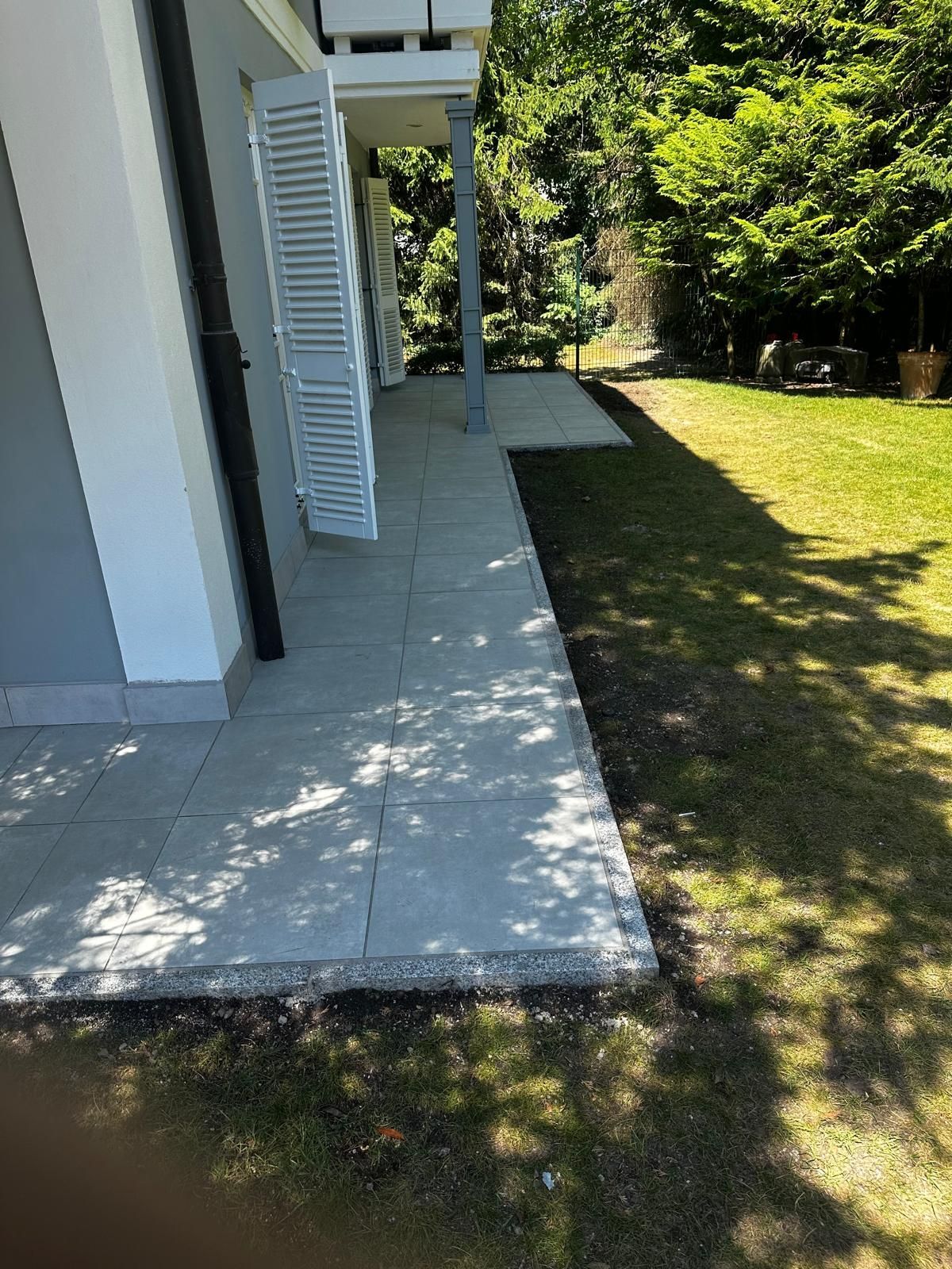 Nachher: Seitliche Ansicht der fertigen Terrasse in Obermenzing mit großformatigen Platten und Granit-Randsteinen durch BE Gartenbau München