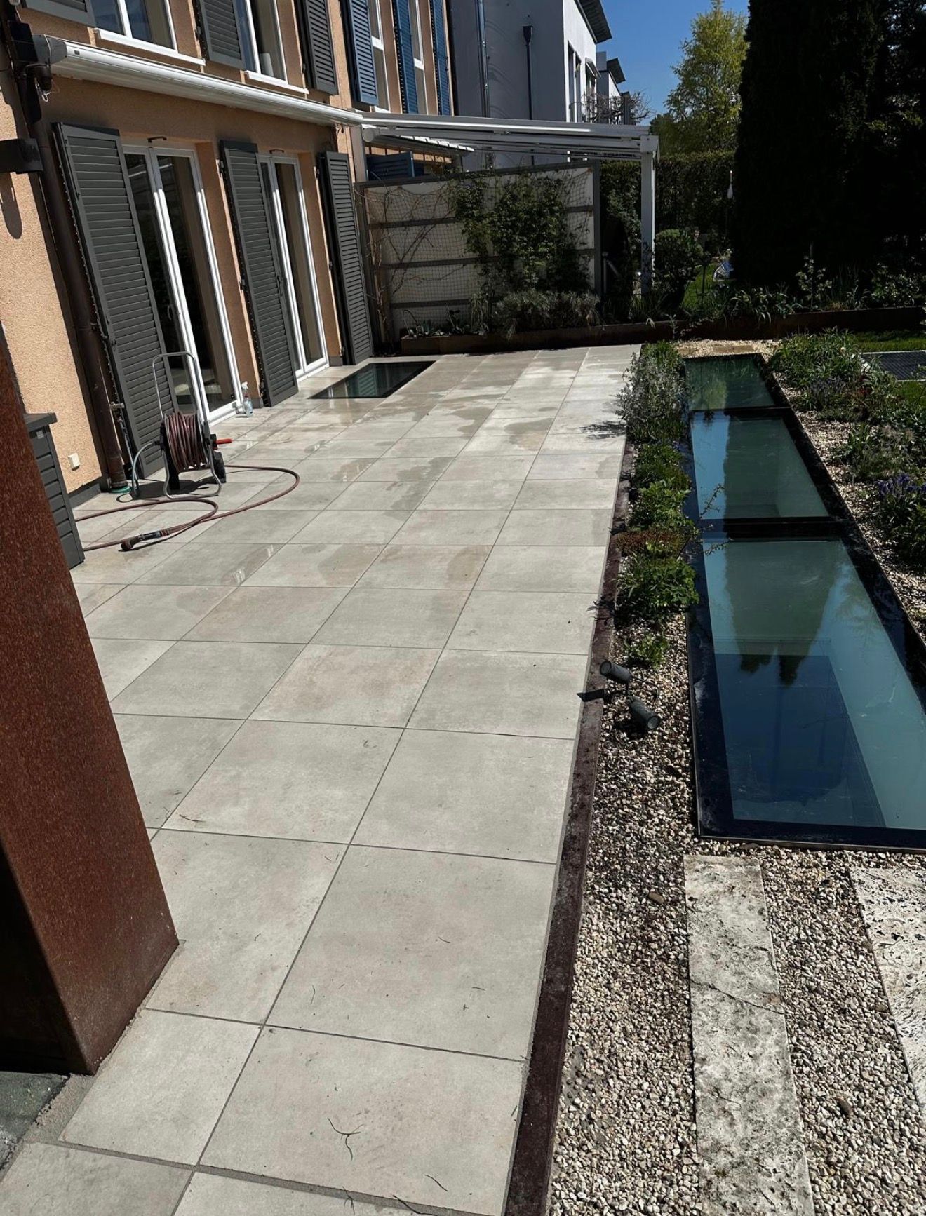 Nachher: Moderne großzügige Terrasse mit hellen großformatigen Feinsteinzeug-Platten in Allach-Untermenzing nach dem Terrassenbau durch BE Gartenbau München