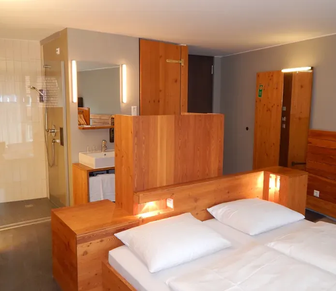 Komfortables Doppelzimmer in Speidel’s BrauManufaktur in Hohenstein – modernes Holzdesign, King-Size-Bett und Balkon.