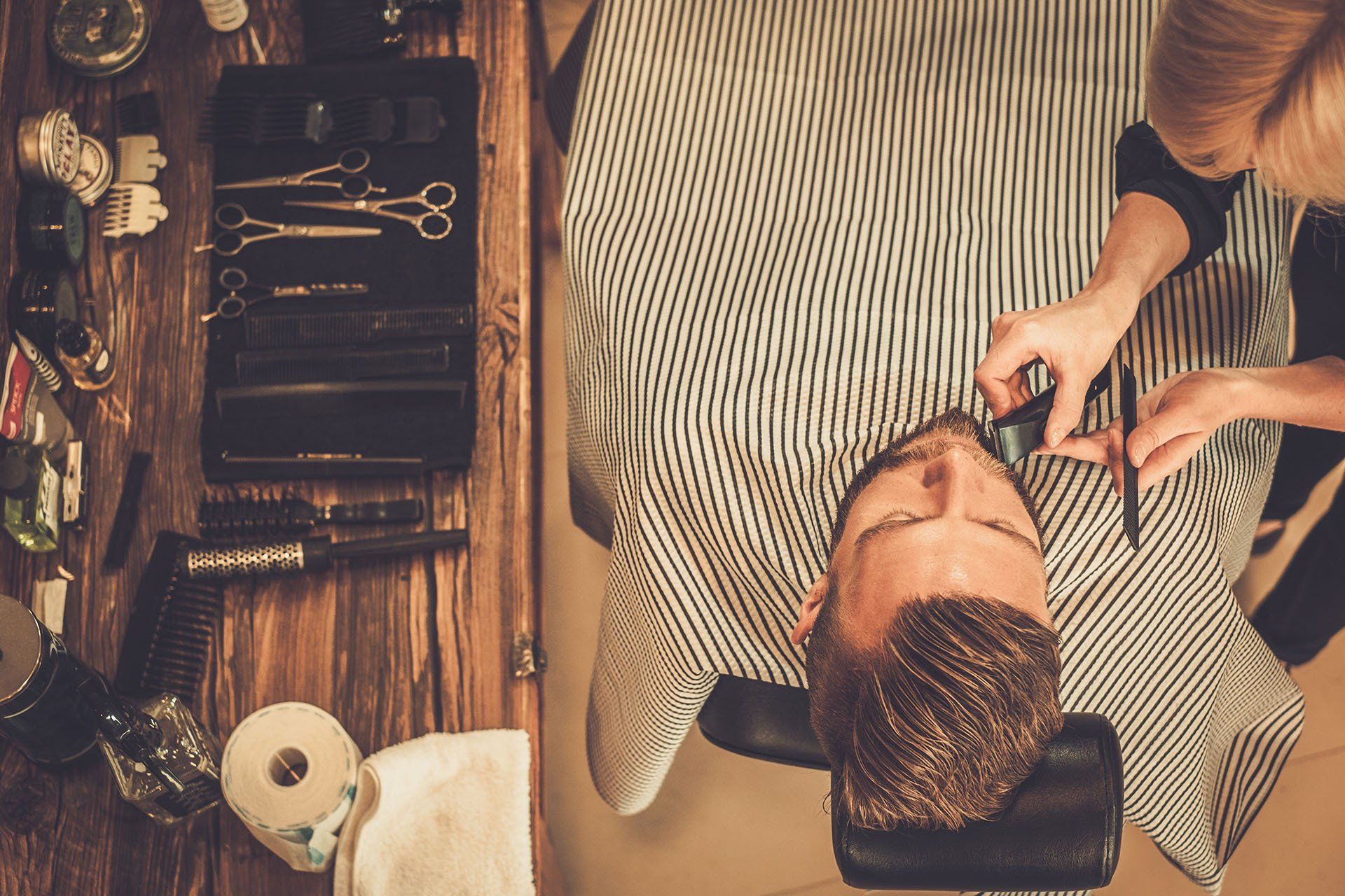a barber and apprentice cutting a mans hair