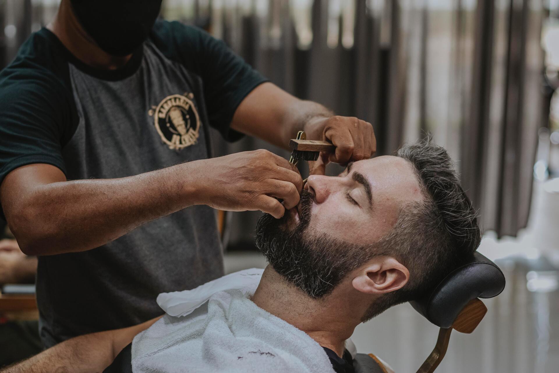 a barber and apprentice cutting a mans hair
