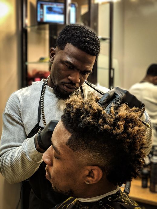 a barber and apprentice cutting a mans hair
