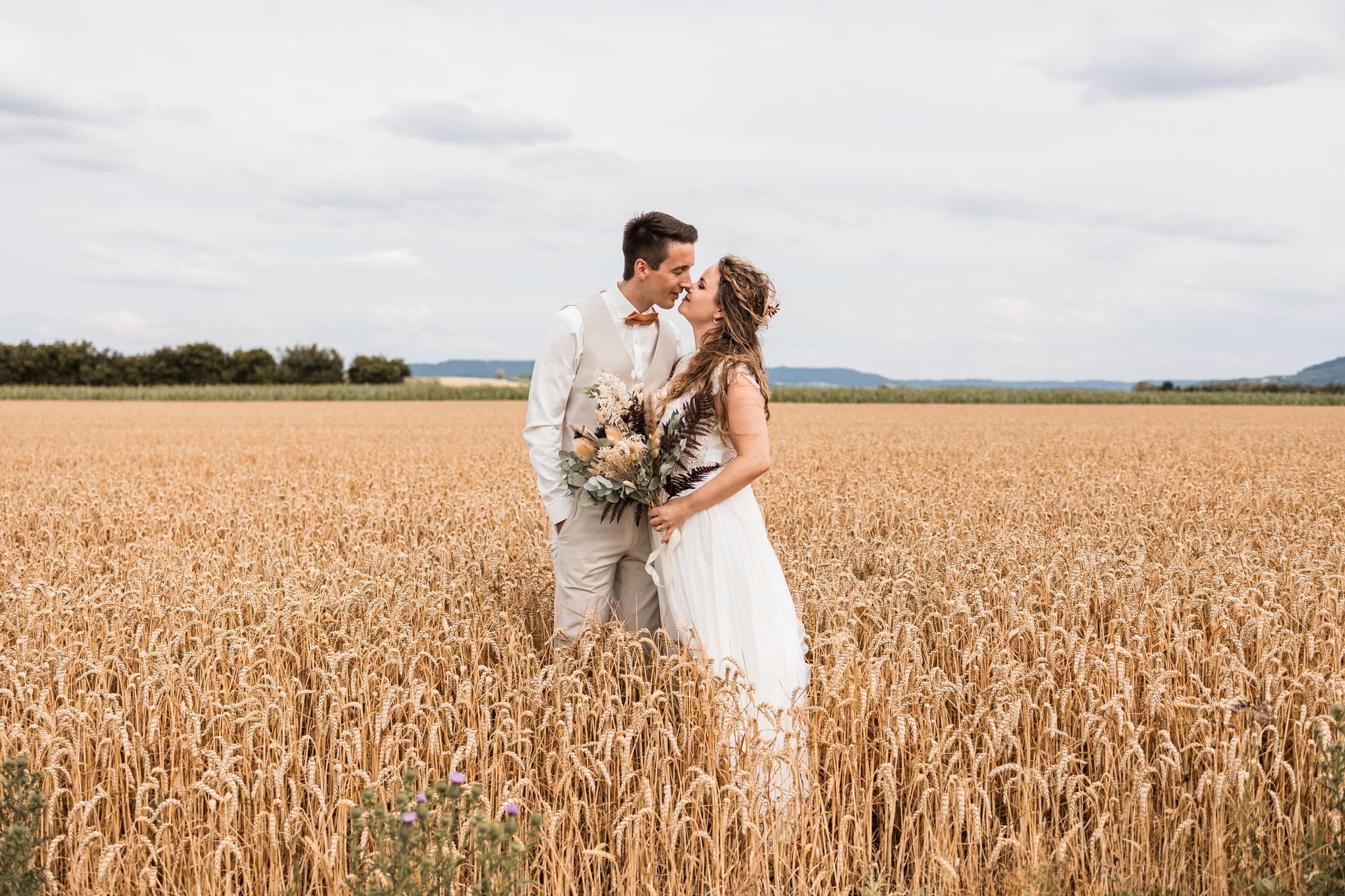 Auf diesem Foto sieht man ein Brautpaar im Feld