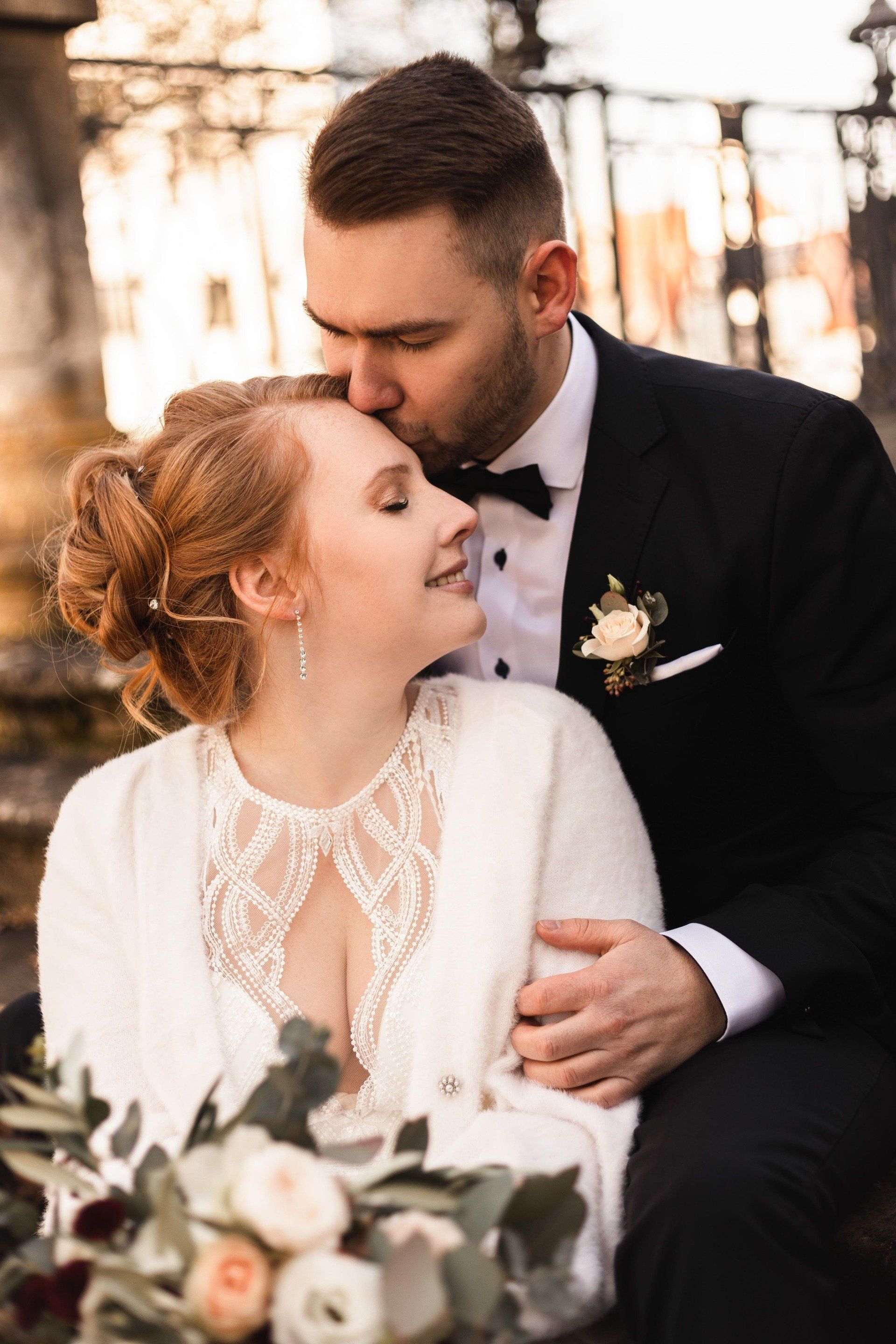 Auf diesem Bild küsst der Bräutigam seine Braut auf den Kopf