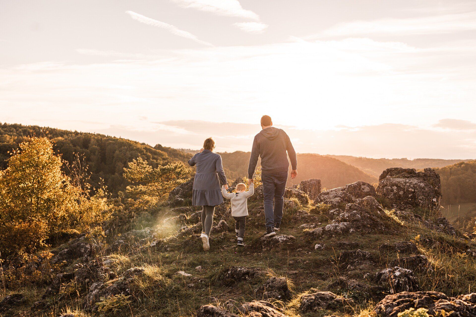 Auf diesem Bild sieht man eine Familie mit Kind im Sonnenuntergang
