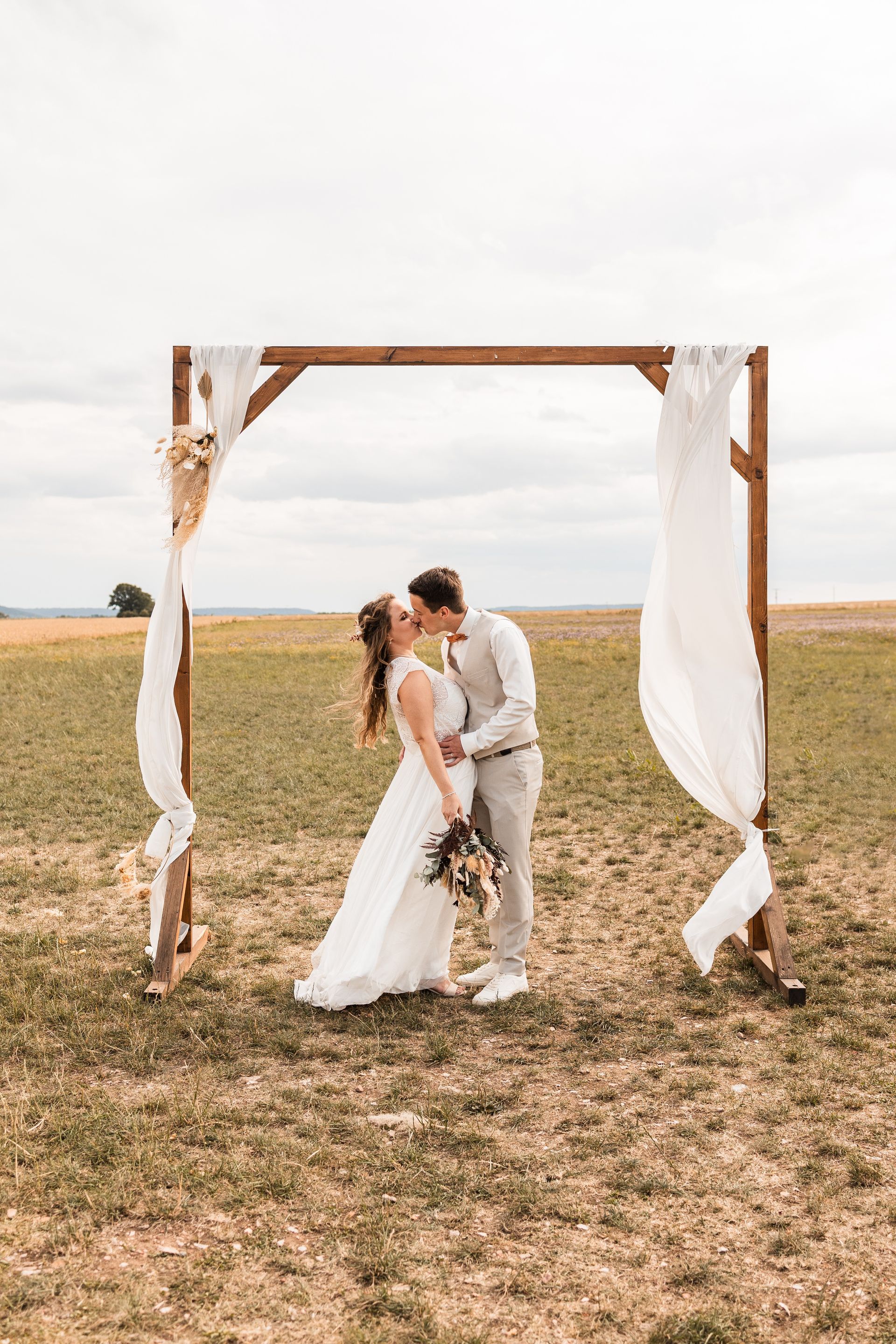 Brautpaar in einem Traubogen Auf diesem Foto sieht man ein Brautpaar in einem Traubogen