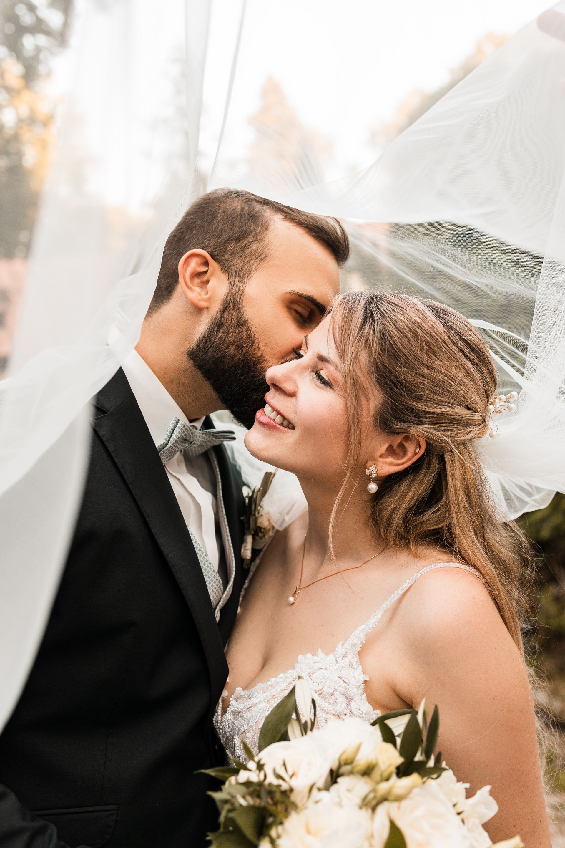 Auf diesem Foto sieht man ein Brautpaar, das unter einem Schleier ist