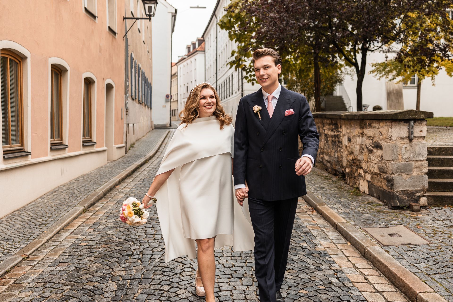 Auf diesem Bild steht eine Braut mit ihrem Brautstrauß vor einer schönen Tür