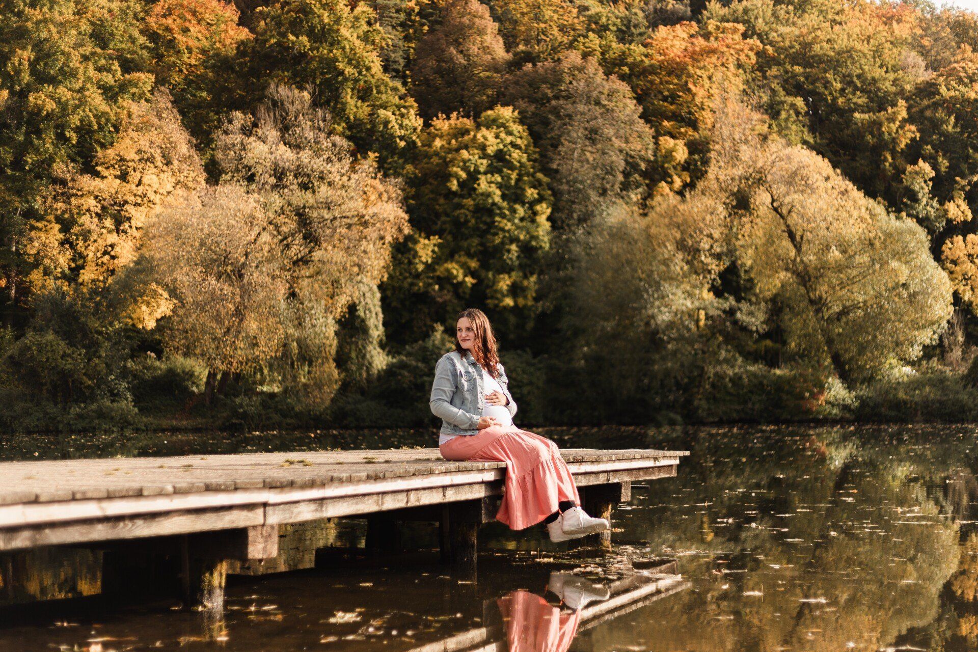 Schwangere Frau am Steg Auf diesem Bild sitzt eine schwangere Frau auf einem Steg