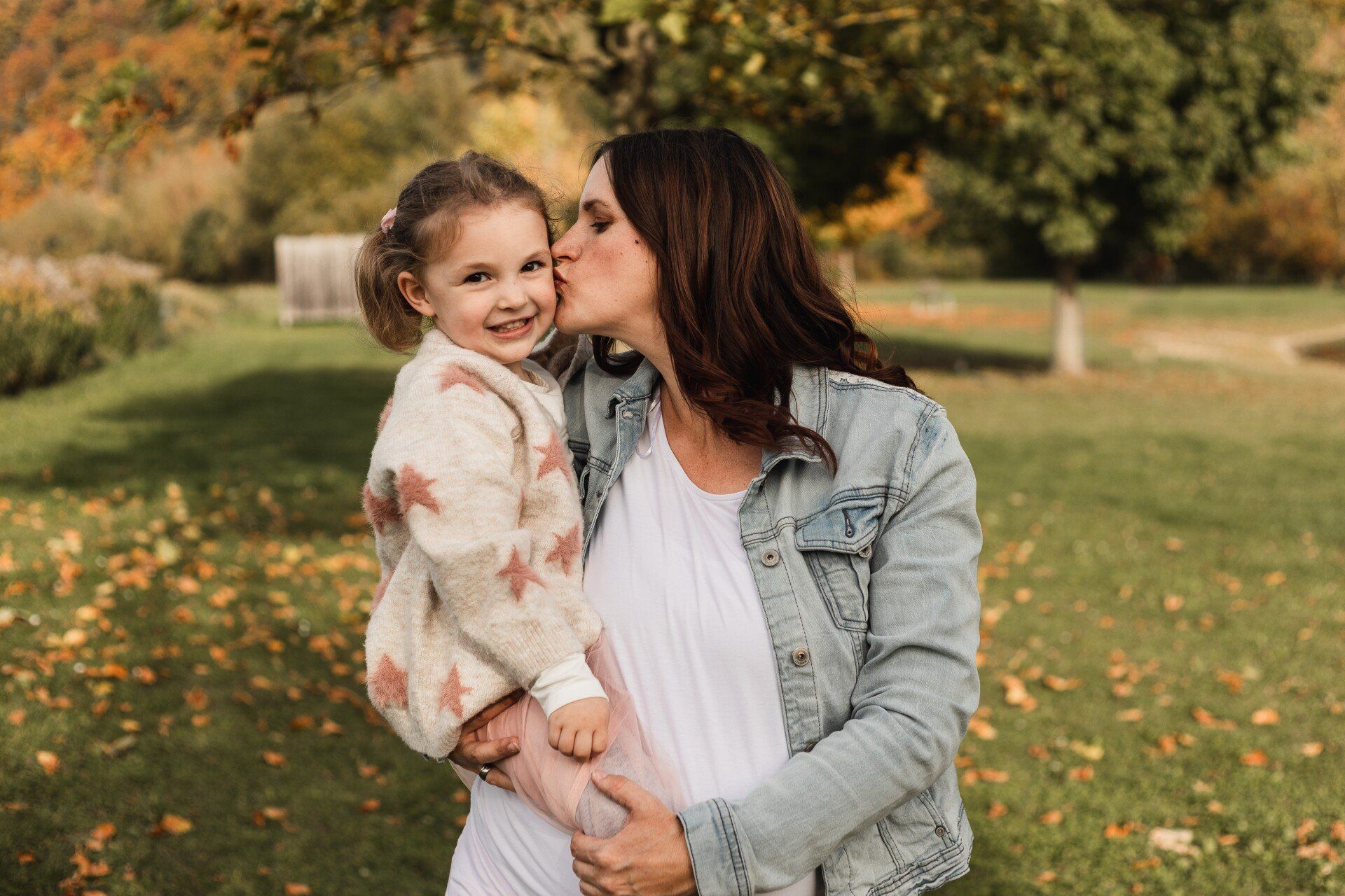 Mutter und Tochter beim gemeinsamen Fotoshooting Auf diesem Bild gibt die Mutter ihrer Tochter einen Kuss auf die Wange