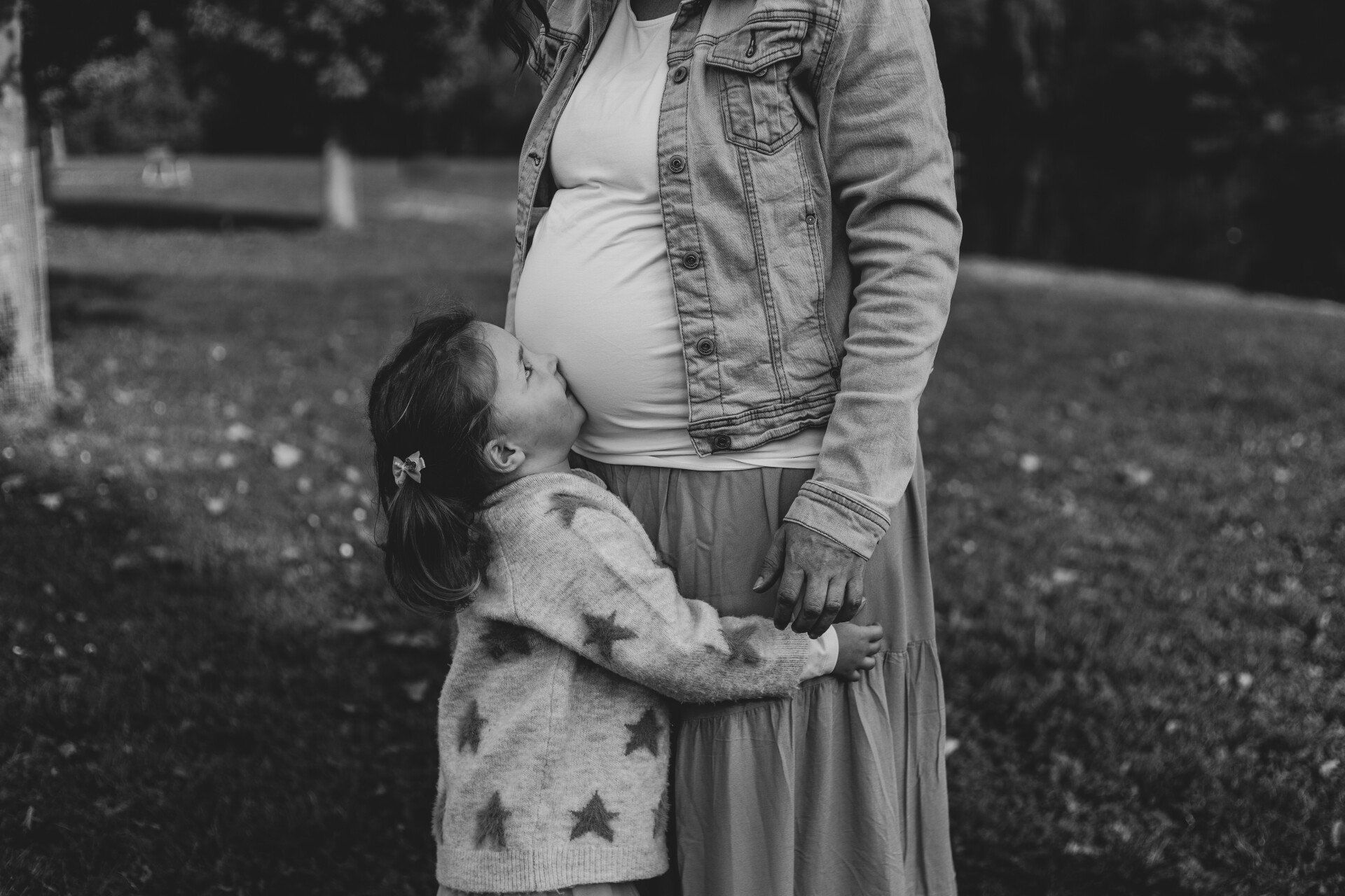 Kind küsst Babybauch Auf diesem Bild küsst die Tochter den Babybauch der schwangeren Mutter