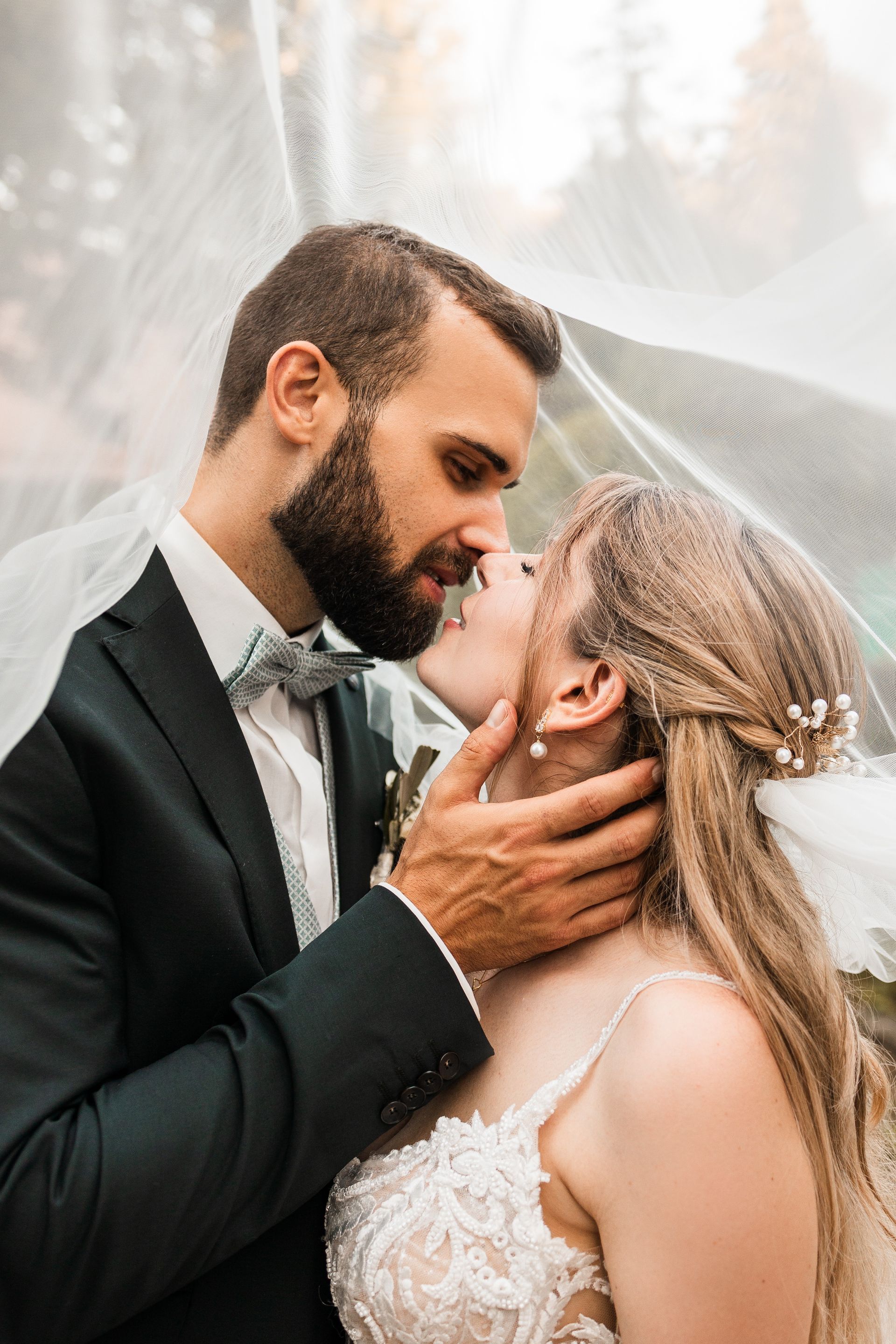 Auf dem Bild kuschelt ein Brautpaar unter einem Schleier
