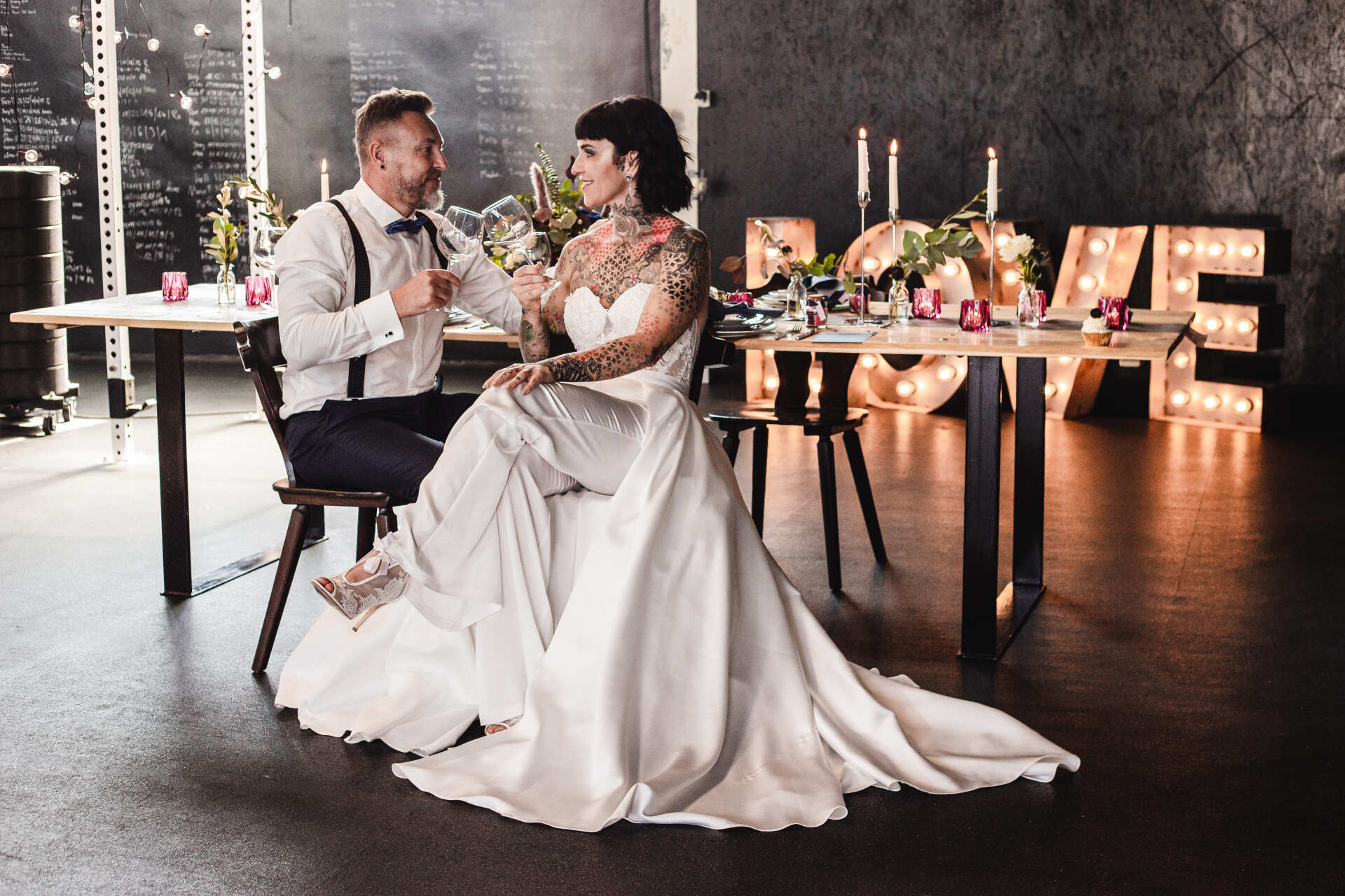 Ehepaar sitzt an ihrem Brauttisch Dieses Bild zeigt ein Brautpaar vor dem Brauttisch beim Fotoshooting