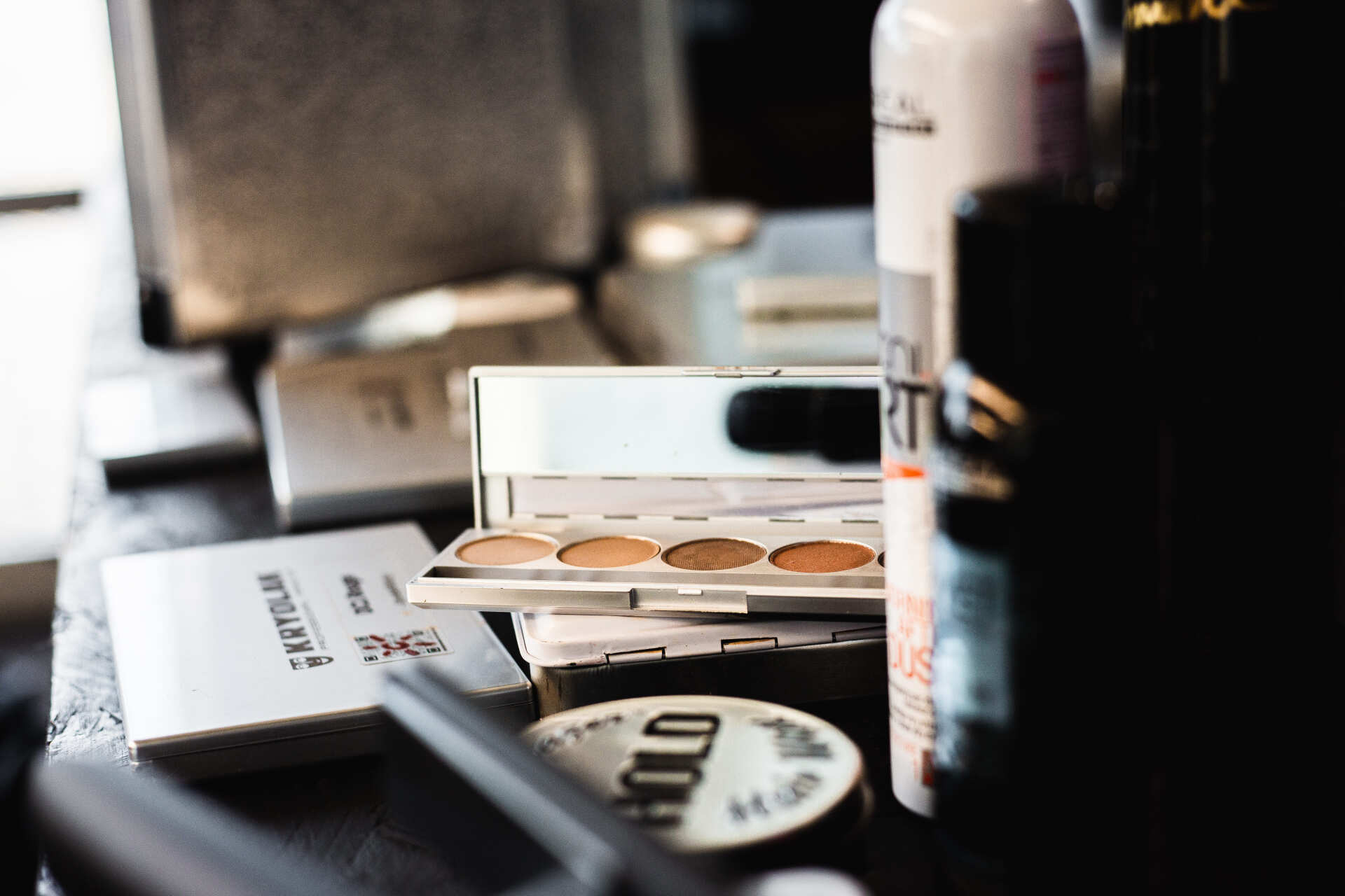 Lidschattenpalette zwischen Haarspray und Makeup Auf dem Foto sieht man eine Lidschattenpalette zwischen Stylingprodukten