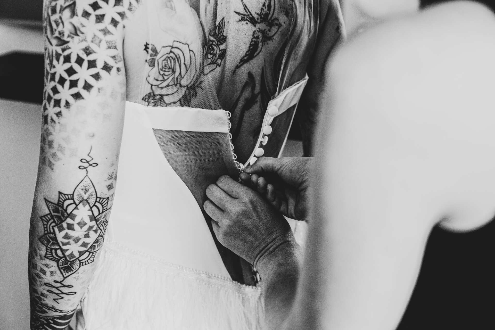 Brautkleid wird mit Hilfe der Brautmodendesignern angezogen Auf dem Bild sieht man, wie das Brautkleid angezogen wird