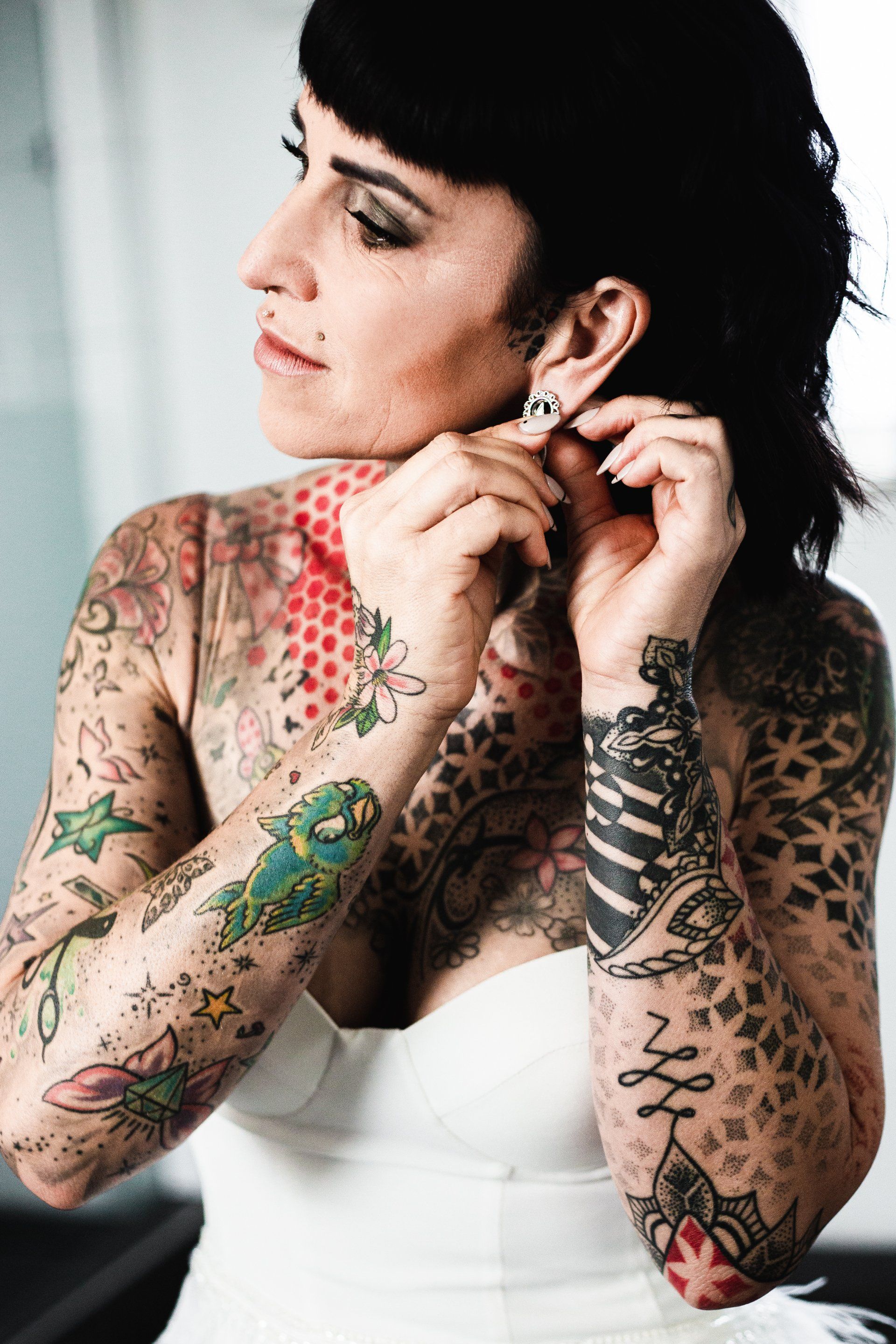 Braut zieht sich Schmuck an Dieses Foto zeigt eine Braut, die sich Ohrringe anzieht