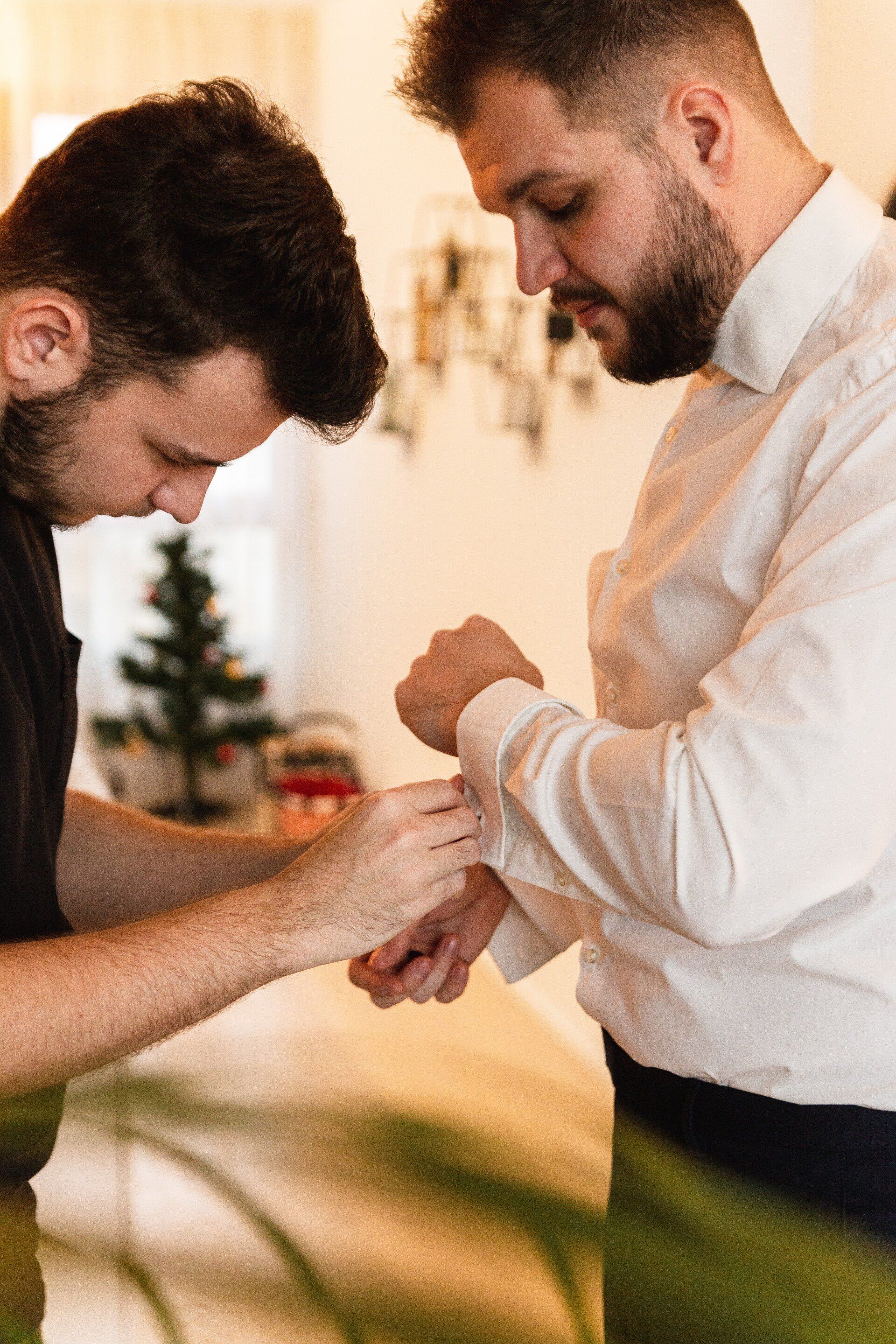Trauzeuge hilft beim Anziehen Auf diesem Bild hilft der Trauzeuge bei den Hemdknöpfen
