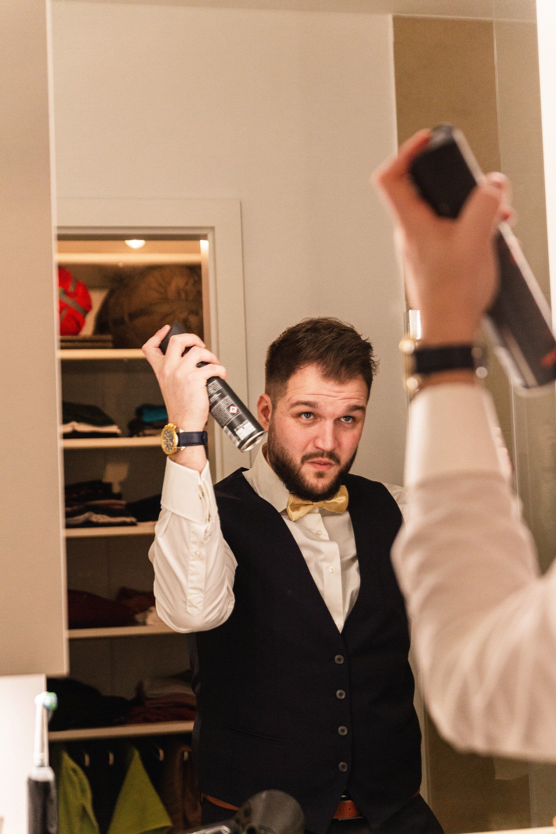 Auf dem Bild fixiert der Bräutigam seine Frisur mit Haarspray