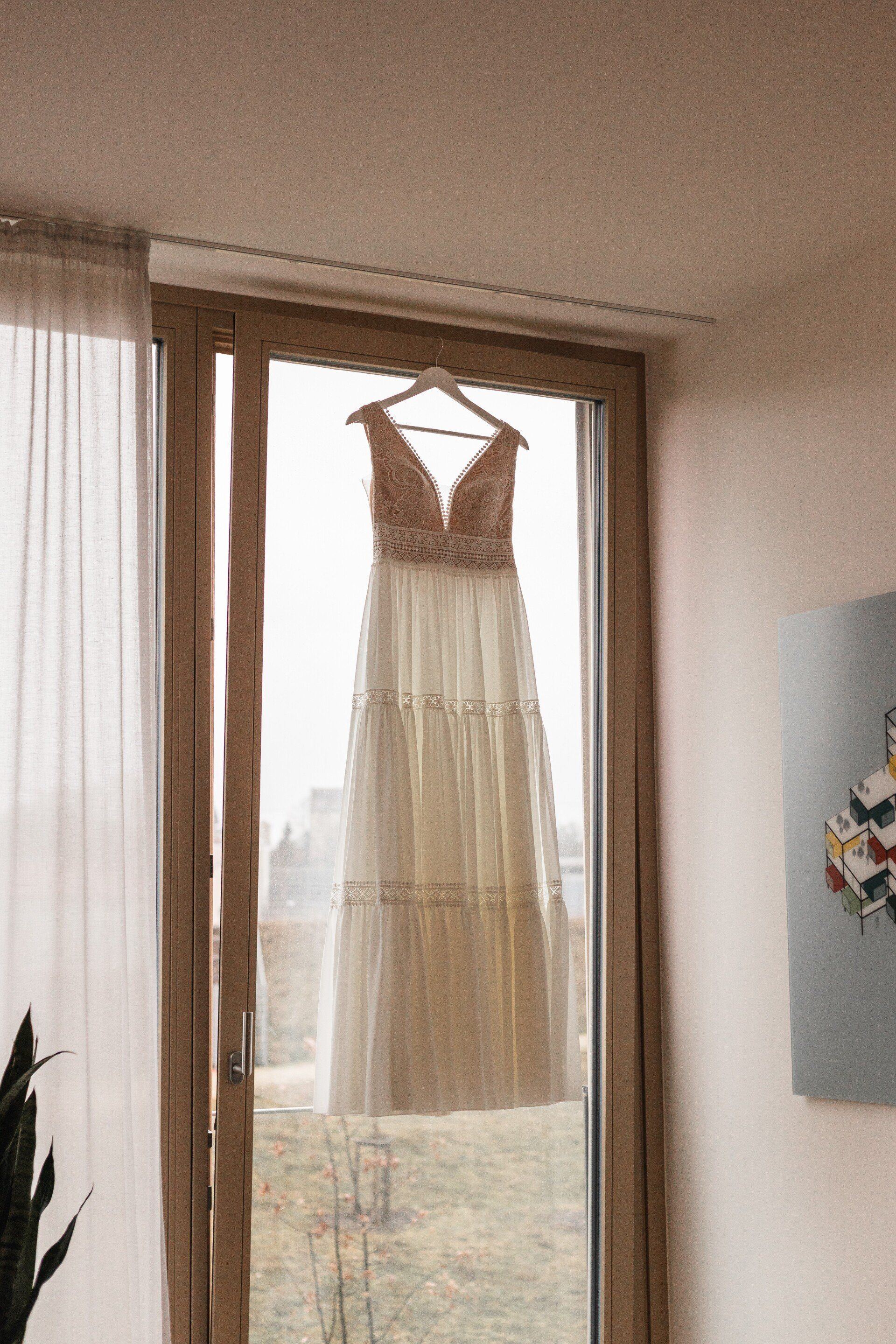 Dies ist eine Aufnahme des Brautkleids, das an einem Fenster hängt