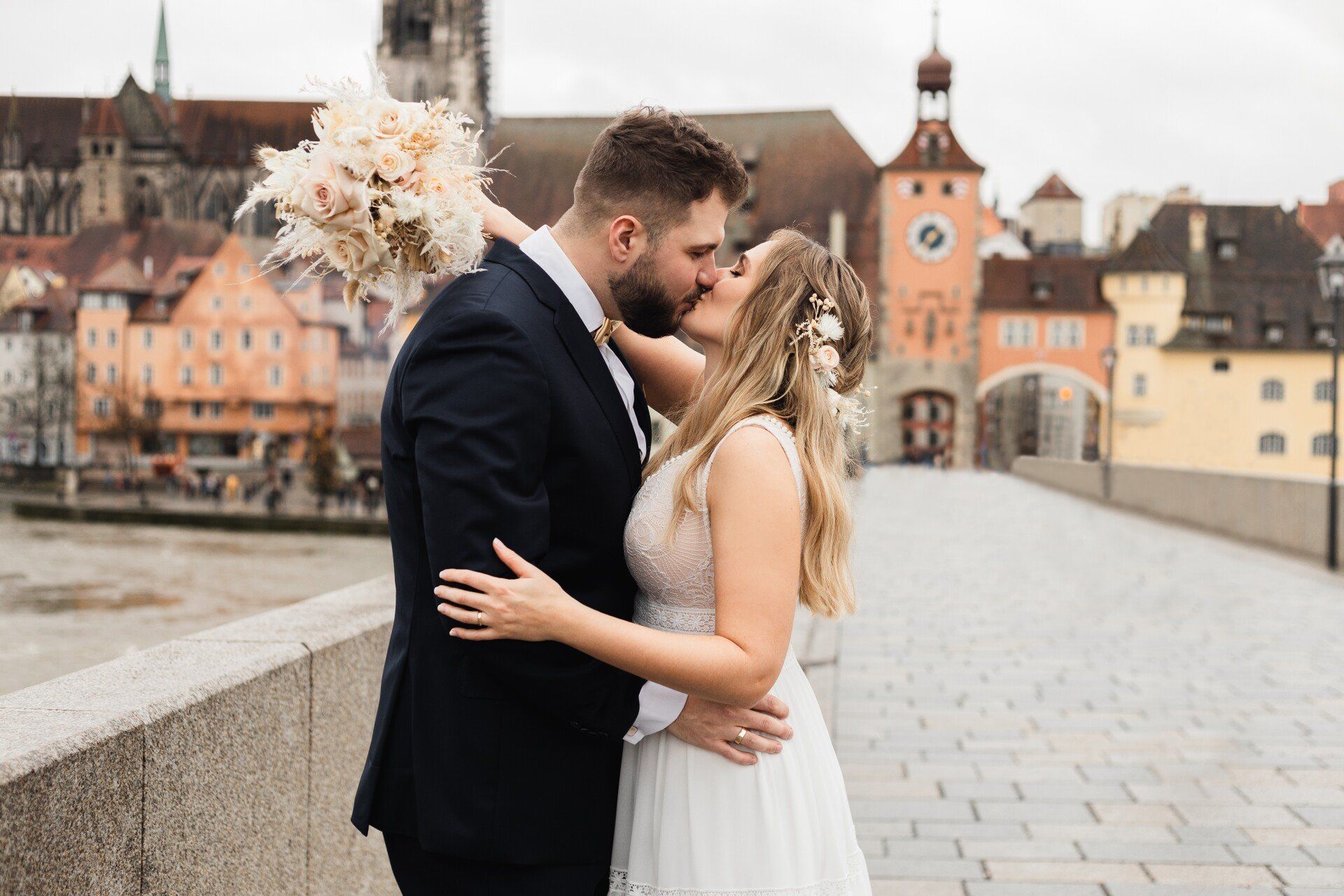 Auf diesem Foto küsst sich das Brautpaar auf der steinernen Brücke Regensburg