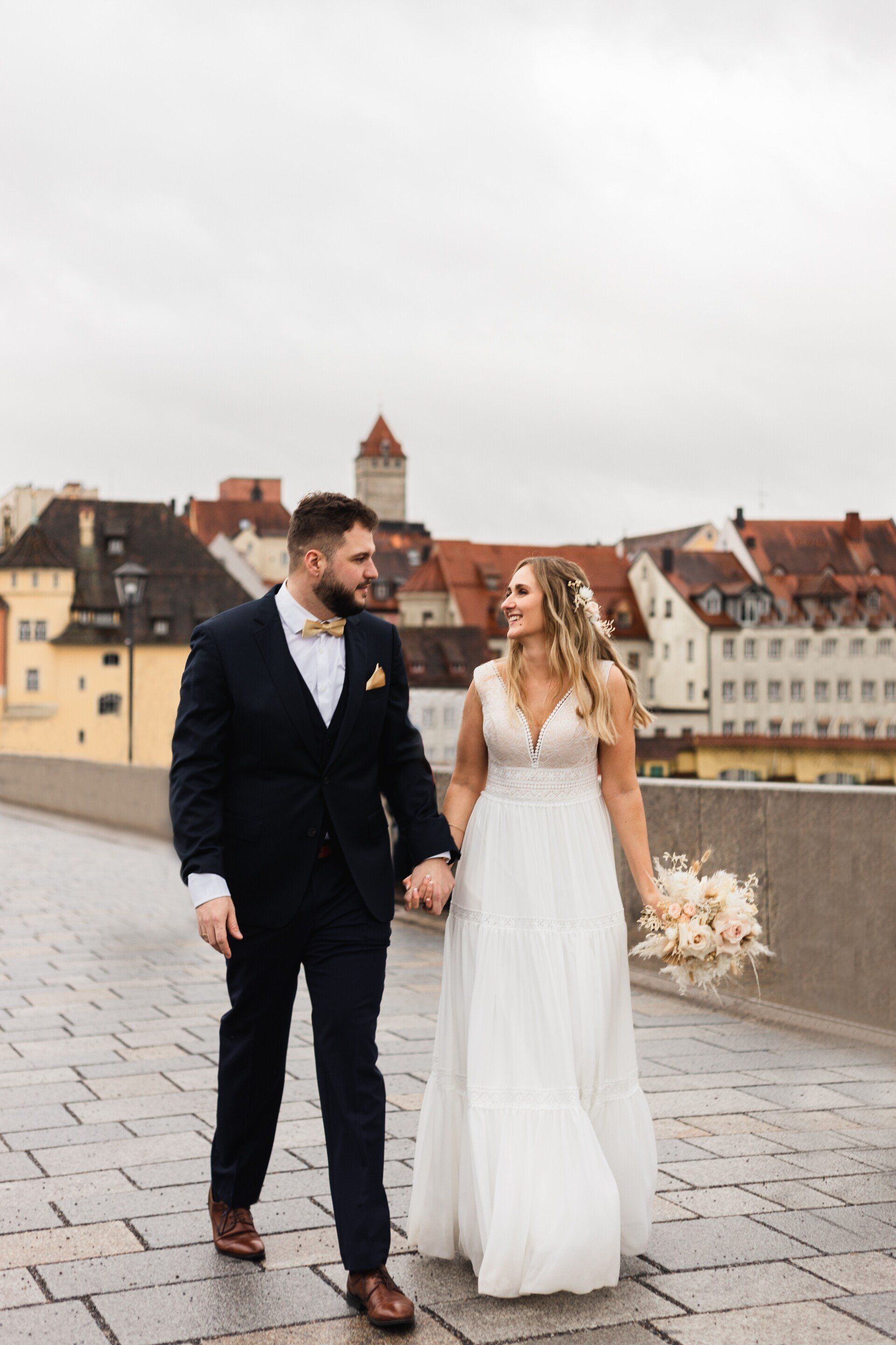 Brautpaar spaziert auf der steinernen Brücke Auf diesem Foto spaziert ein Brautpaar auf der steinernen Brücke in Regensburg